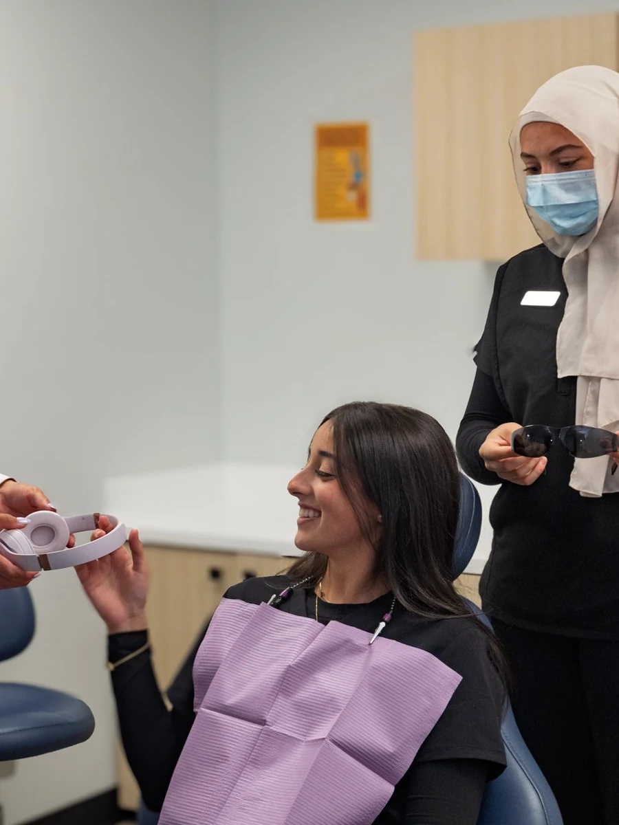 A SmilePro Dental clinician matching a veneer shade against a patient’s smile