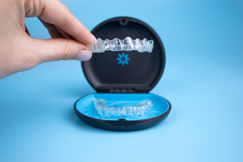 Woman holding invisalign transparent retainers with a box on the