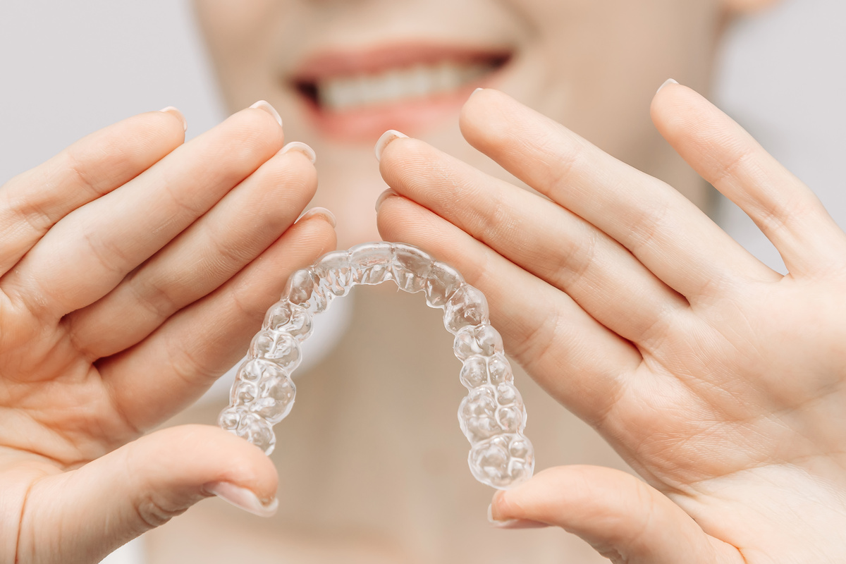 A woman uses an orthodontic silicone trainer for teeth correction. This mobile device highlights modern dental care methods and whitening systems, promoting a healthy and radiant smile.